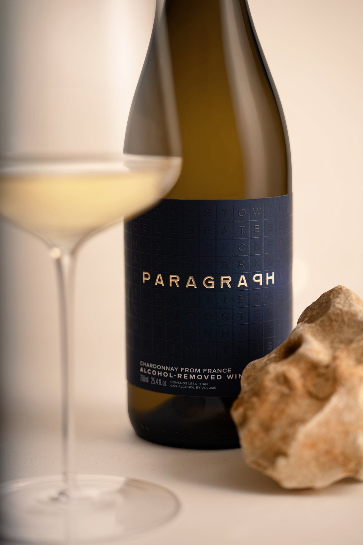 PARAGRAPH Chardonnay label beside a glass of white wine and a stone